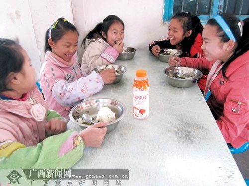 在融水苗族自治县香粉乡中心小学，一群六年级的小学生围坐在食堂里，吃着香喷喷的“免费午餐”。